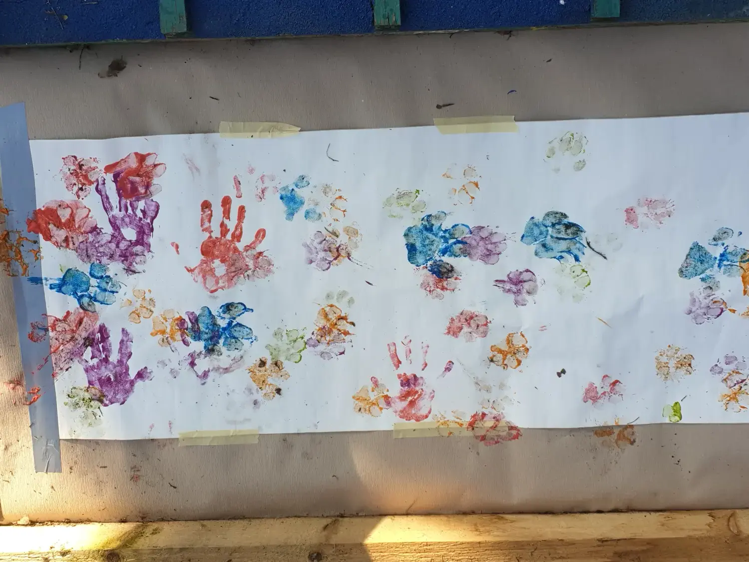 t.t.m.-therapie.tier.mensch.de UG haftungsbeschränkt - Therapeut - ein großes Blatt Papier, das mit verschiedenen Hand- und Pfotenabdrücken mit verschiedenfarbigen Farben bedeckt ist und auf eine kreative Tätigkeit schließen lässt.